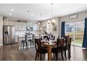 Elegant dining area with modern chandelier, table set, and view of open kitchen and stainless appliances at 14100 Shasta Daisy St, Parker, CO 80134