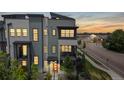 Modern townhome boasts a multi-tone color scheme, inviting red door, and sunset view at 6799 Navajo St, Denver, CO 80221