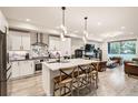 Open-concept kitchen with stainless steel appliances, island with seating, and modern finishes at 6058 Beeler Ct, Denver, CO 80238