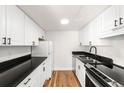 Bright kitchen featuring white cabinets, black countertops, stainless steel appliances, and hardwood floors at 3315 S Monaco St # B, Denver, CO 80222