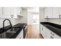 Galley kitchen featuring white cabinets, black countertops, and stainless steel appliances at 3315 S Monaco St # B, Denver, CO 80222