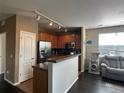Kitchen with stainless steel appliances and wood cabinetry adjoins a living space with gray furniture and wood floors at 7140 Simms St # 202, Arvada, CO 80004