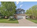 Charming two-story home with blue siding, stone accents, a two car garage, and mature landscaping at 10610 Winterflower Way, Parker, CO 80134