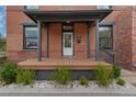 Inviting front porch with wooden flooring, gray columns, and manicured landscaping at 2560 Champa St, Denver, CO 80205
