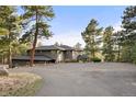 Expansive driveway leading to a well-maintained home surrounded by mature trees and natural landscape at 28890 Pinewood Vista Dr, Evergreen, CO 80439