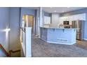 Open-concept kitchen featuring white cabinets, a breakfast bar, stainless steel appliances, and neutral-colored walls at 12948 E 106Th Way, Commerce City, CO 80022