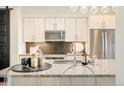 Bright kitchen island with a sink, countertops, and ample storage with stainless steel appliances at 3198 Blake St # 502, Denver, CO 80205