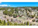 Secluded red home with outbuilding nestled on a hillside with trees at 548 Coughlin Meadows Rd, Boulder, CO 80302