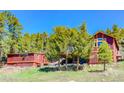 Rustic red home and outbuilding situated among tall trees, offering a serene and secluded setting at 548 Coughlin Meadows Rd, Boulder, CO 80302