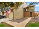 Charming townhome features a brick facade, attached garage, sidewalk, and American flag at 15323 E Louisiana Ave, Aurora, CO 80017