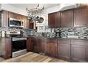 Modern kitchen with dark cabinets, stainless steel appliances, and stylish backsplash and hanging pot rack at 4620 Blackhawk Way, Denver, CO 80239