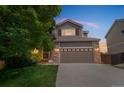 Charming two-story home featuring a two-car garage with lights at dusk at 2446 S Gibralter Way, Aurora, CO 80013
