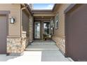 Charming front entrance featuring stone accents, covered porch and modern entry door at 11136 Sweet Cicely Dr, Parker, CO 80134