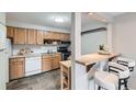 Functional kitchen with wood cabinetry, white appliances, and a breakfast bar for casual dining at 1008 N Corona St # 205, Denver, CO 80218