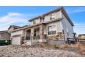 Stylish two-story home showing attached garage, stone accents, tidy landscaping, and architectural detail at 14221 Ivanhoe St, Thornton, CO 80602