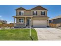 Two-story home with a covered porch, an attached two-car garage, and a well-maintained lawn at 1005 Ryland Rd, Brighton, CO 80603