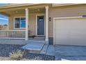 Home's inviting front porch and entryway with a blue door and a convenient attached two-car garage at 1005 Ryland Rd, Brighton, CO 80603