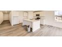 Open-concept kitchen boasts white cabinetry, stainless steel appliances, a center island, and sleek hardwood floors at 22015 E 39Th Ave, Aurora, CO 80019