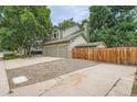A view of the house exterior with a long driveway, two-car garage, and wooden fence at 4858 S Queen St, Littleton, CO 80127