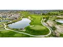 Scenic aerial view of the golf course featuring lush green fairways, a serene pond, and nearby homes at 3940 Malaya St, Denver, CO 80249