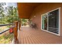 A covered deck has chairs with a small table and sliding glass doors to access the home at 459 Virginia Ave, Palmer Lake, CO 80133