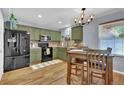 Well-lit kitchen with modern appliances, green cabinets, and a dining area with a decorative chandelier at 165 Montgomery Dr, Erie, CO 80516