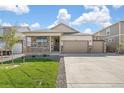 Beautiful home with a well-maintained lawn, stone accents, and a spacious three-car garage at 4723 Windmill Dr, Brighton, CO 80601