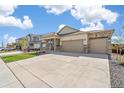 Inviting home exterior with stone accents, a spacious driveway, and lush green lawn at 4723 Windmill Dr, Brighton, CO 80601