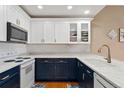 Modern kitchen with white upper cabinets, blue lower cabinets, and stainless steel appliances at 6000 W Floyd Ave # 214, Denver, CO 80227