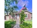 Charming brick home with a lush front yard, pergola entrance, and an American flag at 1965 Havana St, Aurora, CO 80010