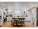 Well-lit, modern kitchen with white cabinets, stainless steel appliances, and a rustic island with stools at 8367 Devinney St, Arvada, CO 80005