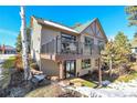 Tan two-story home with a walk out deck showcasing outdoor seating in a sunny wooded neighborhood at 1294 Red Lodge Dr, Evergreen, CO 80439