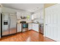 Well-lit kitchen featuring stainless steel appliances, white cabinetry, and hardwood floors at 1160 S Clinton St # 40, Denver, CO 80247