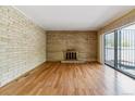 Cozy living room with hardwood floors, a brick wall and fireplace, and sliding glass doors to a patio at 1160 S Clinton St # 40, Denver, CO 80247