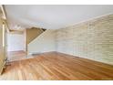 Open living area with hardwood flooring, light brick wall, and staircase in view at 1160 S Clinton St # 40, Denver, CO 80247
