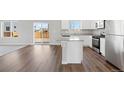 Open-concept kitchen and living room with hardwood floors and sliding glass doors at 7303 Dolores Ave, Frederick, CO 80530