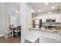 Bright kitchen with white cabinets, stainless steel appliances, and granite countertops open to dining area at 8391 S Upham Way # 209, Littleton, CO 80128