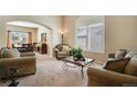 Bright living room with neutral carpet, arched doorway, and a large window with plantation shutters at 11830 Snowshoe Dr, Parker, CO 80138