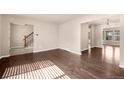 Open-concept living room with hardwood floors and neutral walls leading to stairway and sunroom at 4643 S Vivian Ct, Morrison, CO 80465