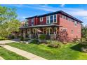 Attractive two-story home with a covered front porch, manicured lawn, and sidewalk at 13324 W 86Th Dr, Arvada, CO 80005