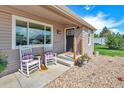 A cozy front porch featuring classic rocking chairs, colorful flower pots, and easy access to the front door at 1775 Longbranch St, Strasburg, CO 80136
