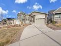 Street view showcasing a home with a large driveway, manicured lawn, and architectural design at 8894 River Peak Cir, Littleton, CO 80125