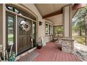 Inviting front porch with rocking chairs, stone pillars, and a beautifully decorated front door at 7737 Taylor Cir, Larkspur, CO 80118