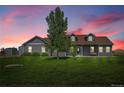 Charming single-story home with lush lawn, mature trees, and gray siding at dusk at 177 W 8Th Ave, Byers, CO 80103