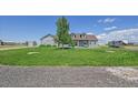 Single-story home with lush lawn, mature trees, gray siding, and storage shed at 177 W 8Th Ave, Byers, CO 80103