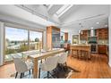 Bright, open kitchen and dining area featuring hardwood floors, a large island, and stainless steel appliances at 7250 W Vassar Ave, Lakewood, CO 80227