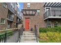 Close-up of a brick townhouse entrance featuring a vibrant red door and well-kept landscaping at 1325 Jackson St, Denver, CO 80206
