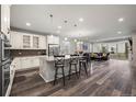 Open-concept living space with a kitchen, dining table, hardwood floors, and access to the patio at 22669 E Tufts Pl, Aurora, CO 80015