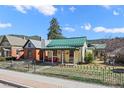 Charming home with a green metal roof, covered porch, fenced yard, and well-manicured lawn at 829 Colorado Blvd, Idaho Springs, CO 80452