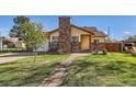 Charming home featuring a brick chimney, well-manicured lawn, and a welcoming front walkway at 5420 E 61St Way, Commerce City, CO 80022